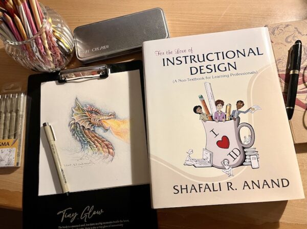 The drawing of a dragon and the book "For the Love of Instructional Design" by Shafali R. Anand